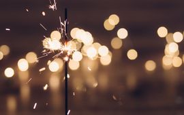 Burning sparkler on blurred background.