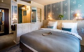 A light-flooded sample room in the new hotel Marias Platzl, which is furnished with a large bed and lots of light wood and colours