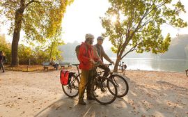 Two sporty cyclists in the English Garden Munich in front of a small lake.