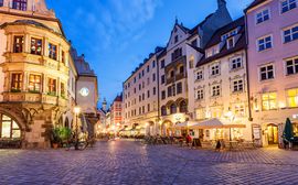 Der attraktive Straßenzug Platzl im Herzen Münchens mit schönen Häuserfassaden bei Nacht.