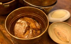 Freshly baked rustic bread in a copper pot served with butter and spread