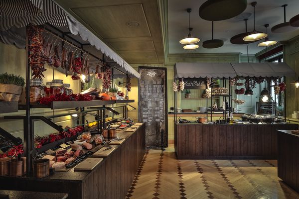 A cozy breakfast room features a large wooden buffet with meats, cheeses, bread and fresh herbs