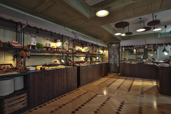 Ein gemütlicher Frühstücksraum verfügt über ein großes Holzbuffet mit Fleisch, Käse, Brot und frischen Kräutern