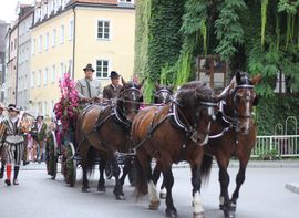 Eine Kutsche, mit zwei Männern, wird von vier Pferden in München gezogen