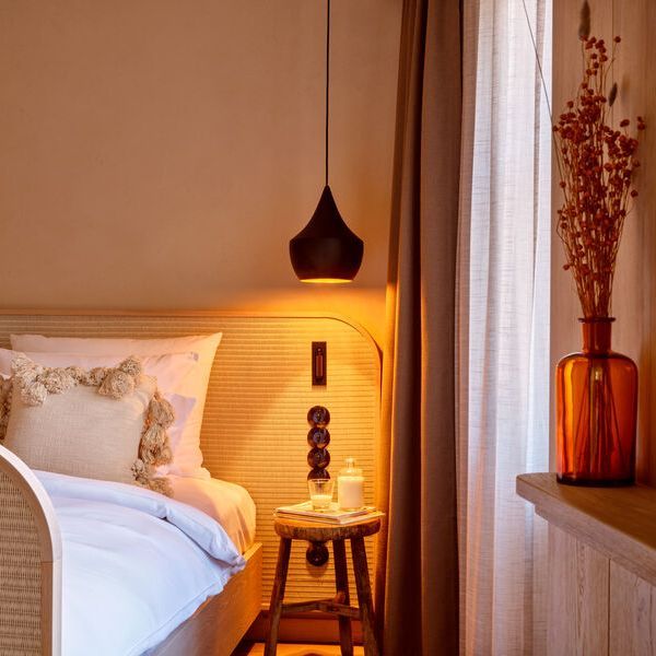 Aufnahme einer neuen Suite im Platzl Hotel mit moderner Lampe, Nachttisch, gemütlichem Bett & Vase.