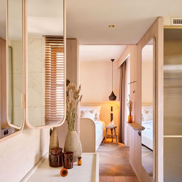 Blick aus dem Bad in den Schlafbereich des in Brauntönen gestalteten Hotelzimmers.
