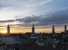 Die Skyline Münchens beim Sonnenaufgang mit dem Turm des alten und neuen Rathauses, des alten Peters, der Frauenkirche und der Heilig-Geiste Kirche.
