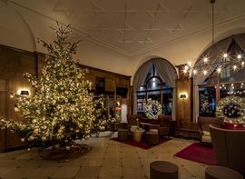 Weihnachtlich geschmückte Lobby des Platzl Hotel in München mit beleuchtetem Tannenbaum 